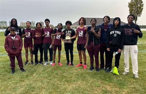 Boys cross country team posing with trophy and coach